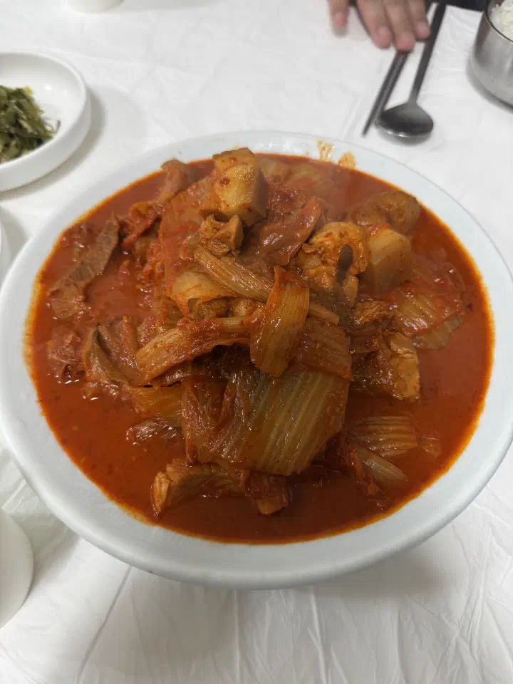 Close-up of aged kimchi and chunks of braised pork in Jeonwon Sikdang’s duruchigi