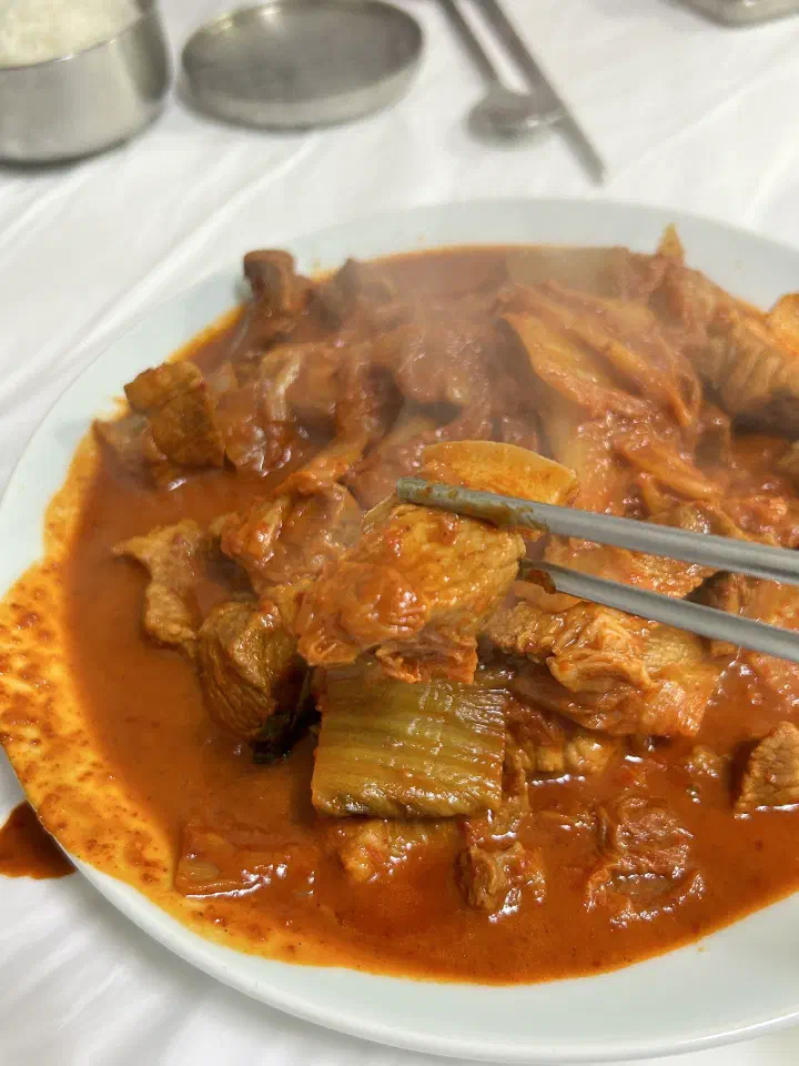 김이 오르는 두루치기에서 고기를 집어 올리는 모습