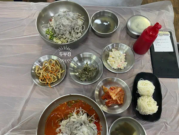 물회 두 그릇과 소면, 김치와 멸치볶음 등 반찬이 차려진 완도회식당 상차림