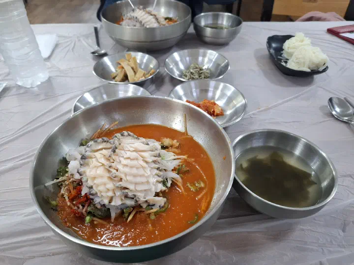 특 사이즈 산오징어물회와 미역국, 소면, 반찬이 놓인 4인 테이블