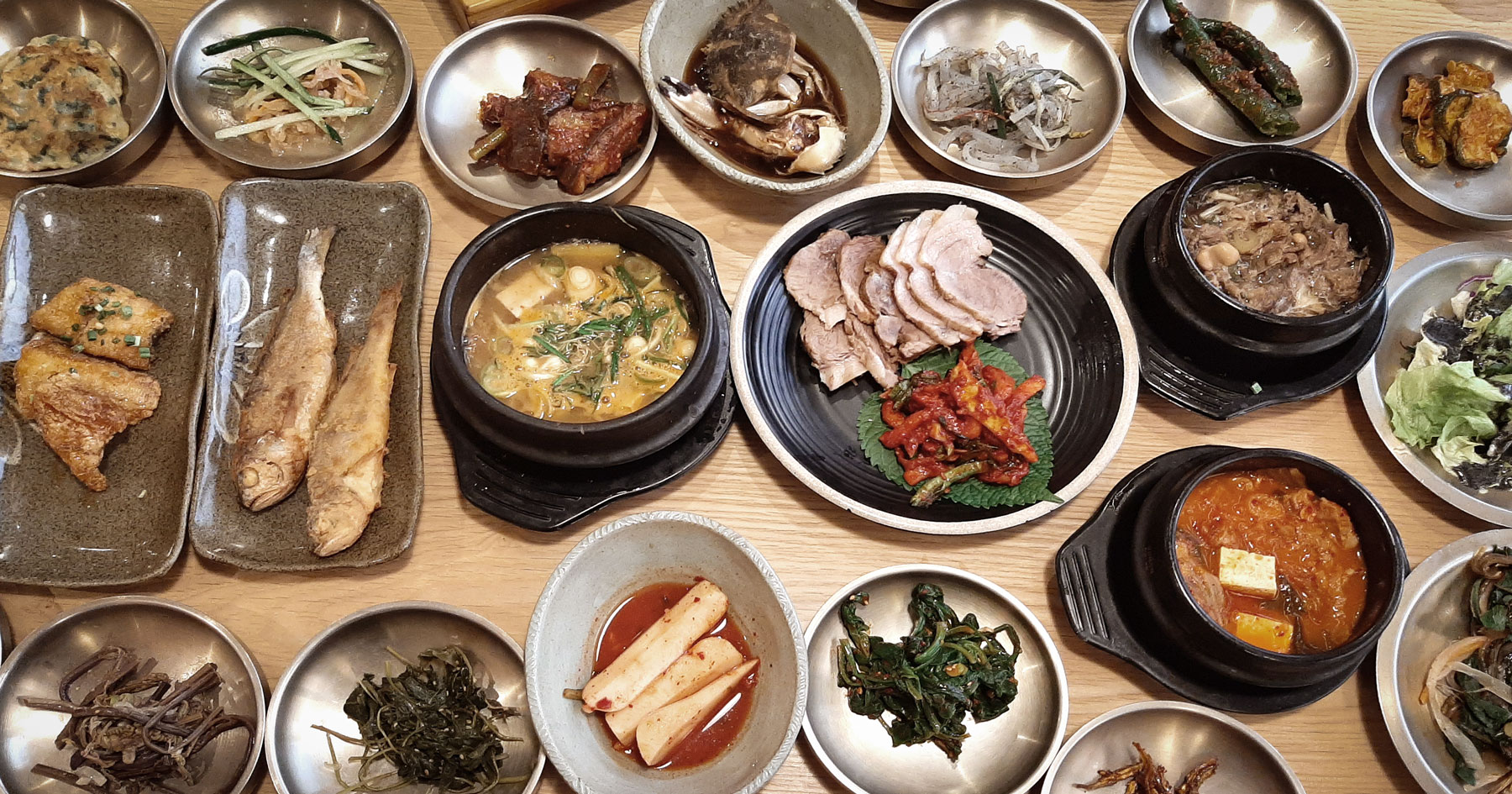 Toenmaru Bapsang Korean set table with about twenty side dishes