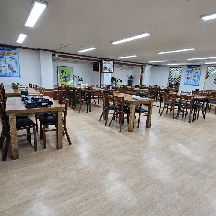 바다예찬 매장 내부 홀에 놓인 원목 테이블과 입식 좌석