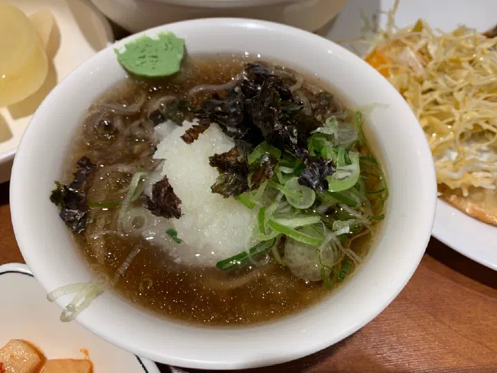 Top view of naengsoba with grated radish, scallions, and shaved ice