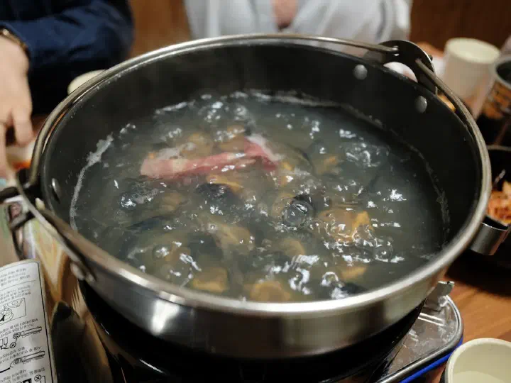 Seafood broth with mussels coming to a boil for shabu-shabu at Cheonghakdong Eonyang Bonjeom