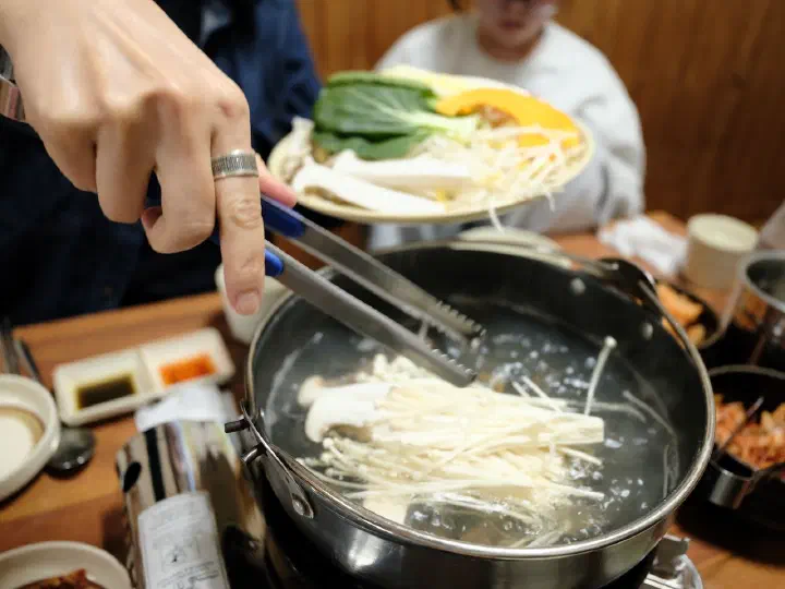 Staff setting up the shabu-shabu at the table at Cheonghakdong Eonyang Bonjeom