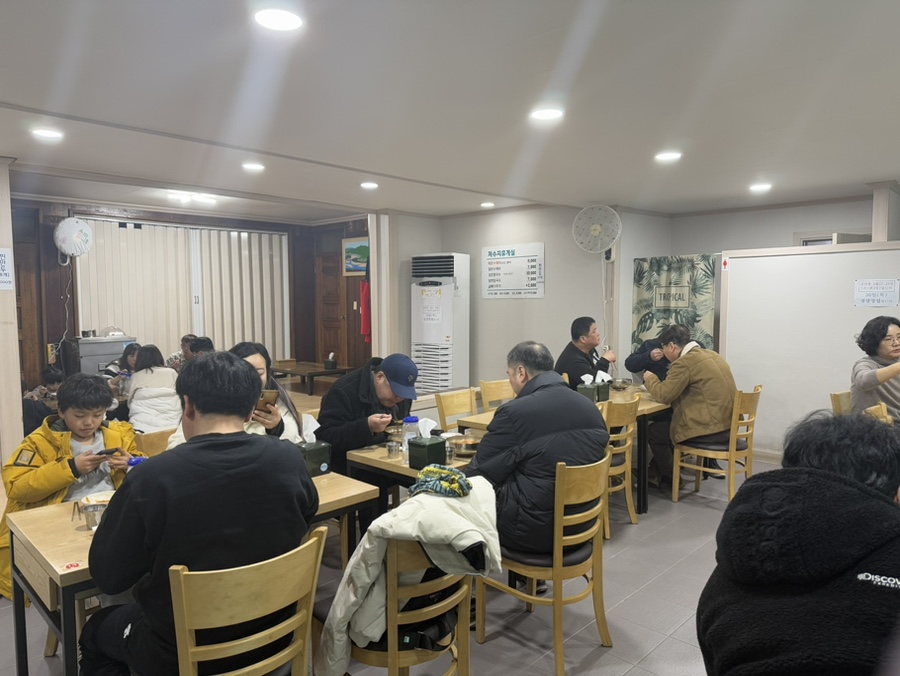 Inside the dining room with customers eating at simple wooden tables