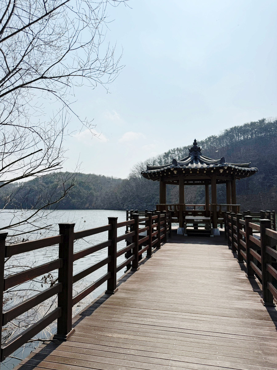 Wooden deck path leading out to a Korean pavilion on Duhyeon Reservoir