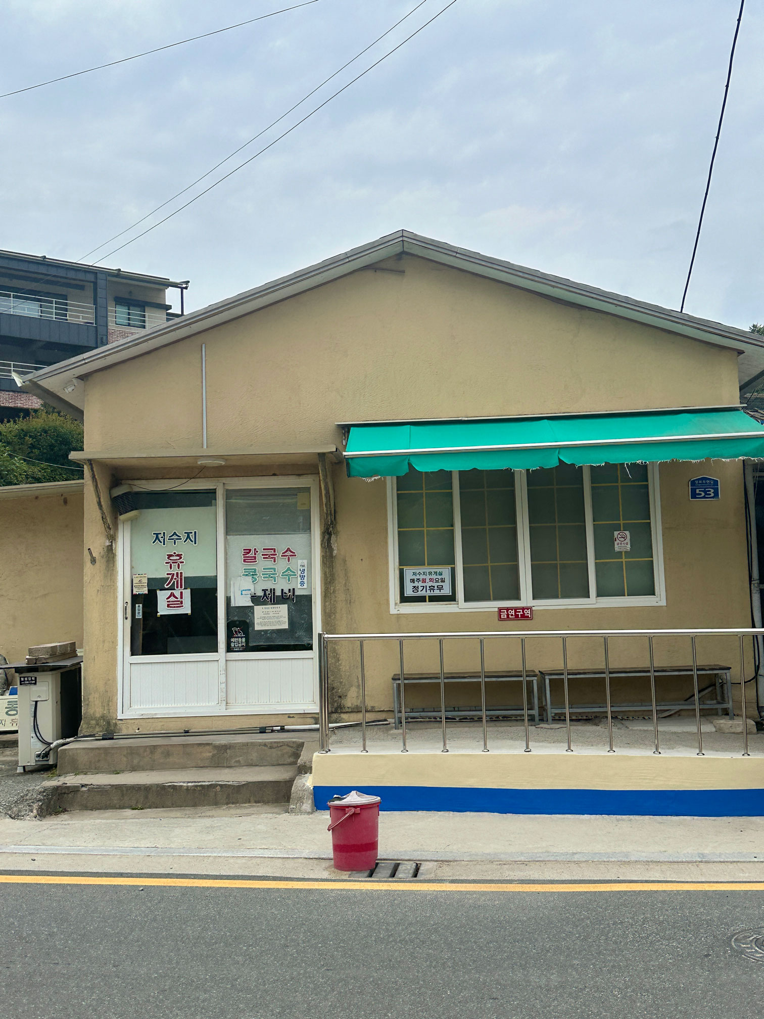 Front view of the yellow single-storey Jeosuji Hyugesil building in rural Ulsan