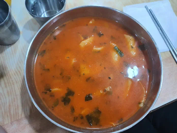 Overhead view of the spicy broth showing sancho dust and chopped bangah leaves