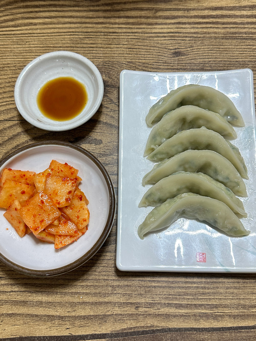 Plate of steamed mandu with cubed radish kimchi on the side