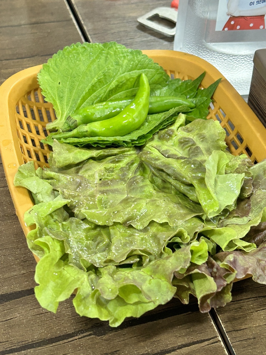 Fresh basket of lettuce, perilla leaves, and green chili peppers
