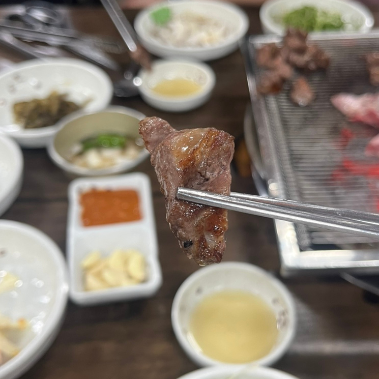 A perfectly grilled bite of galmaegisal on chopsticks