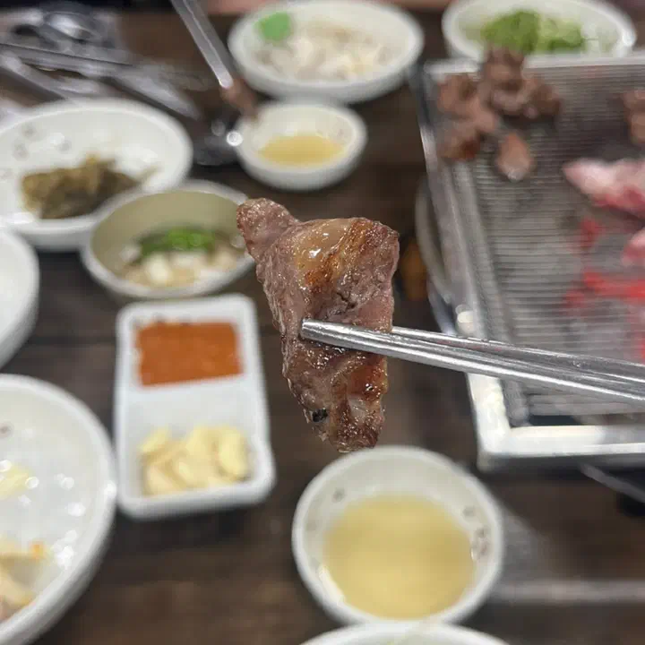 A perfectly grilled bite of galmaegisal on chopsticks
