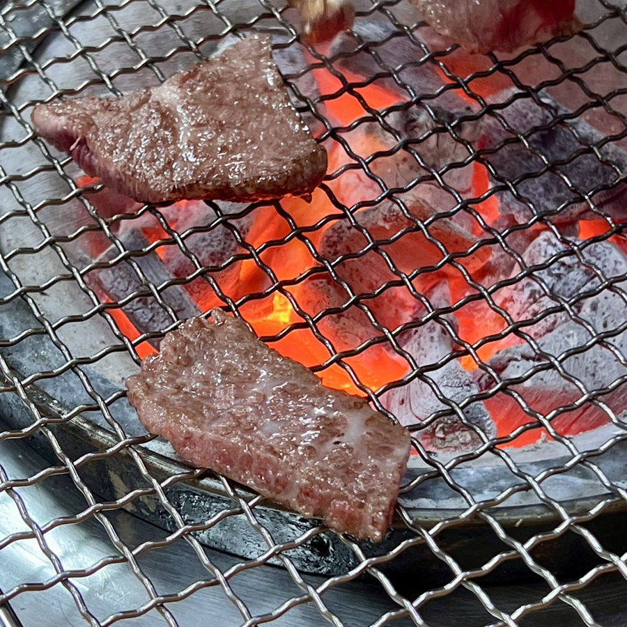 Close-up of Hanwoo galbisal sizzling over glowing charcoal