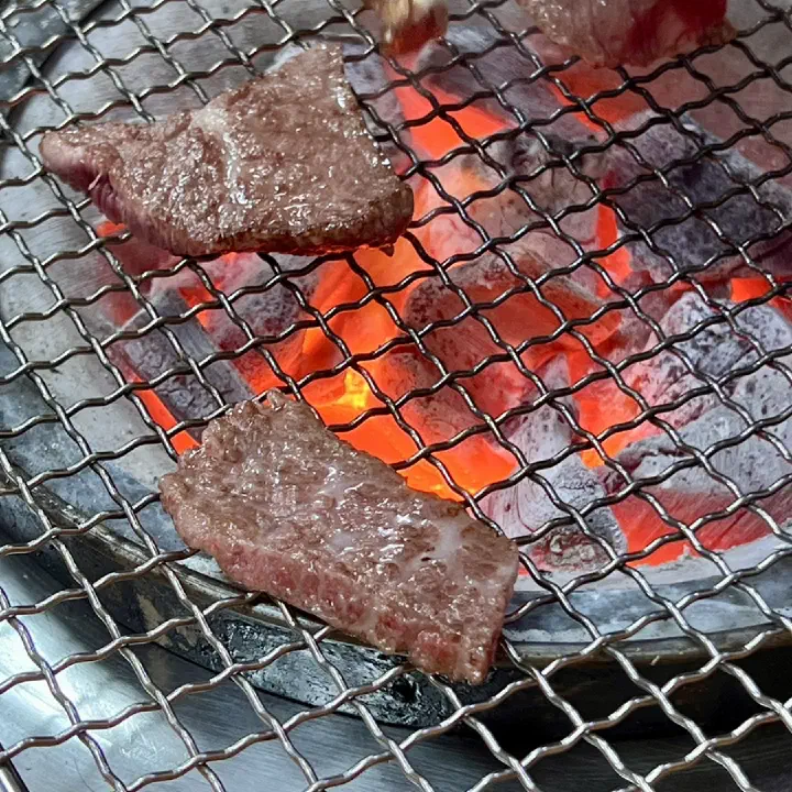 Close-up of Hanwoo galbisal sizzling over glowing charcoal