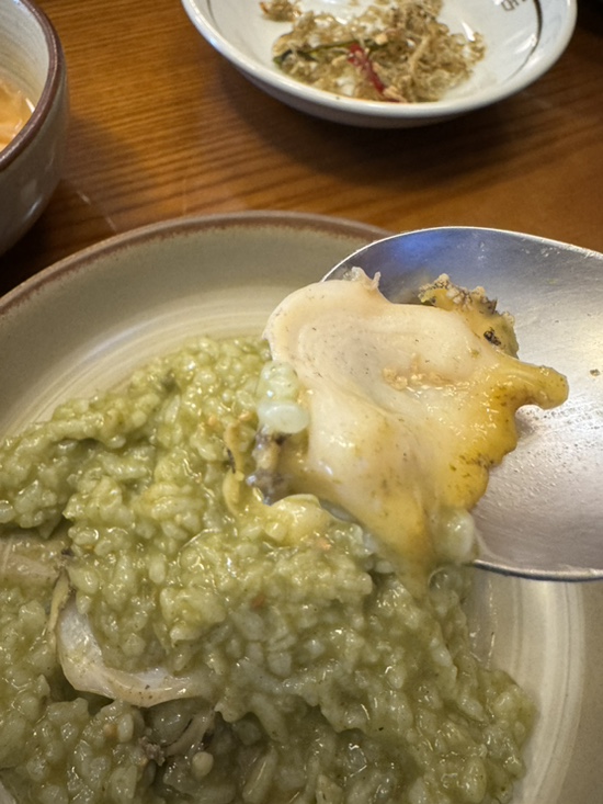 Whole abalone piece on a spoon at Wonjo Jeonbokjuk