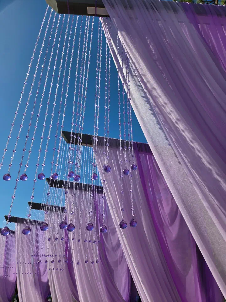 Purple crystal bead strands and sheer curtains against blue sky at the cafe photo zone