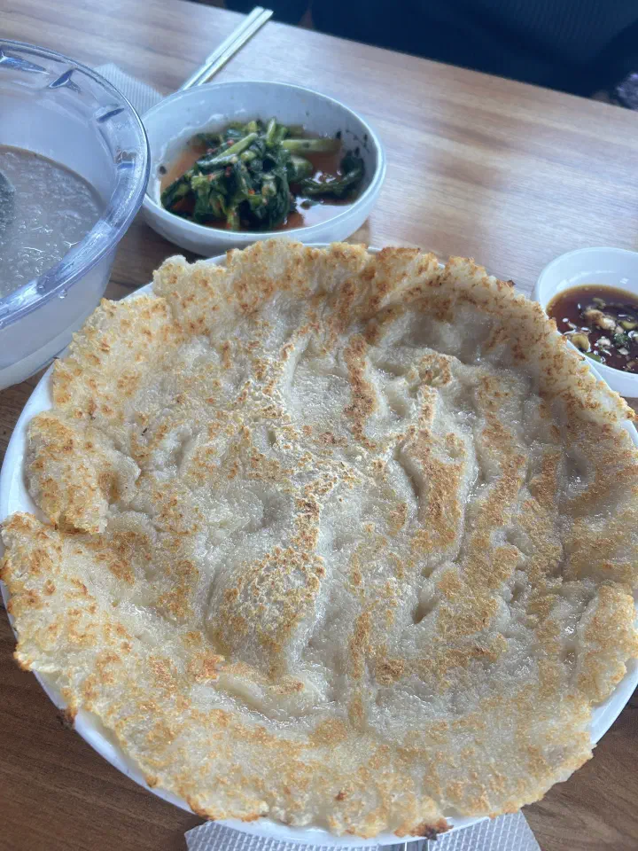 Gangwon-style potato pancake beside a bowl of icy dongchimi broth and young radish kimchi at Yeonggwangjeong