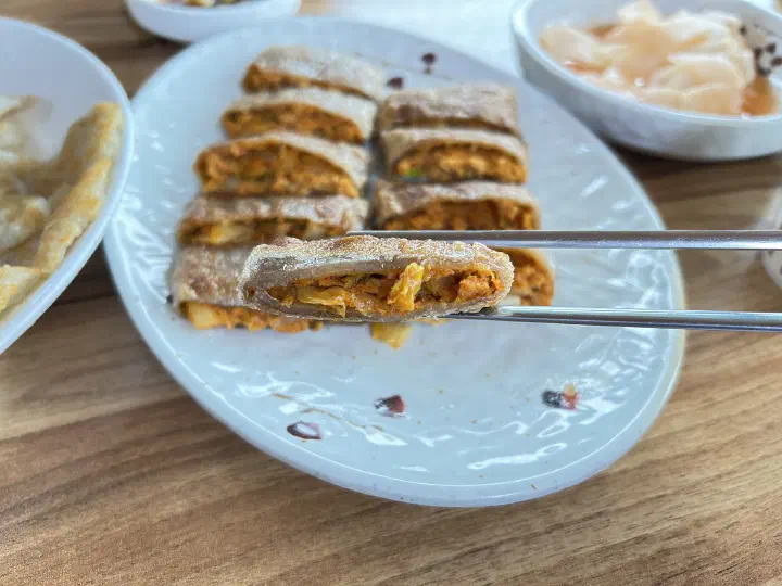 Cut buckwheat crepe roll showing the spicy kimchi filling inside