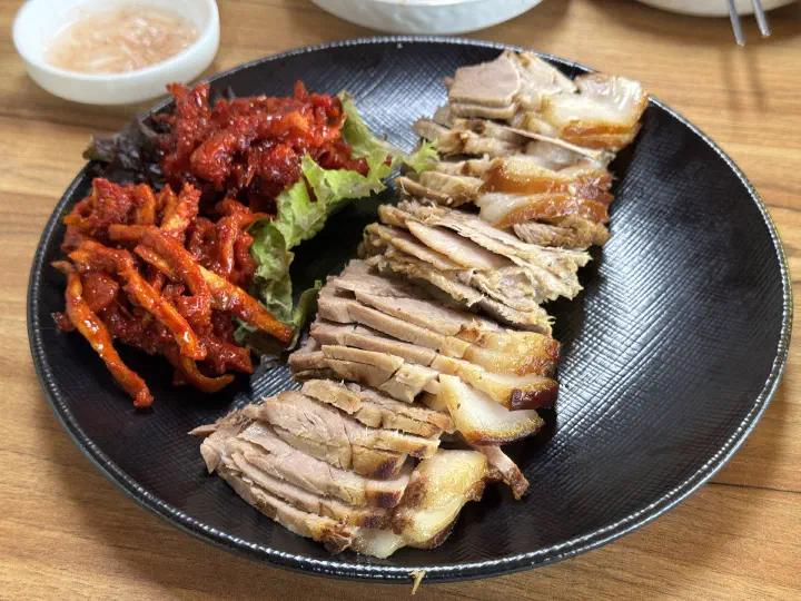 Plate of sliced boiled pork suyuk with spicy pollock salad at Yeonggwangjeong Memil Guksu