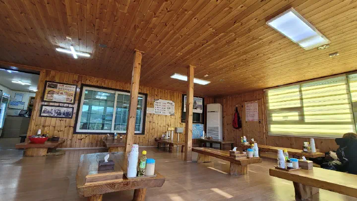 Wide wood-panelled dining hall with log tables inside Yeonggwangjeong Memil Guksu
