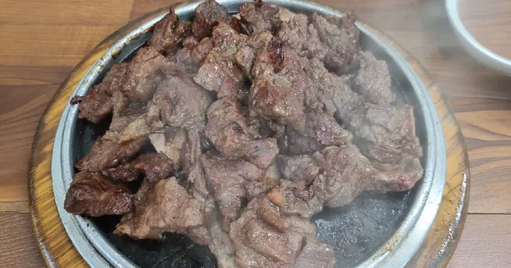 Charcoal-seared beef ribs steaming on a hot stone plate