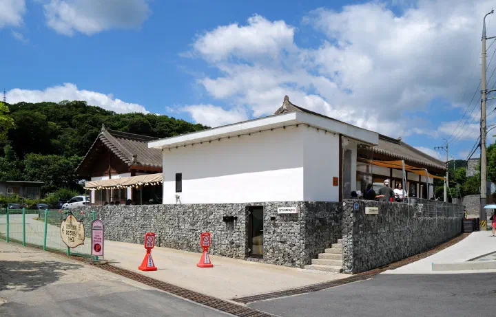 Hanok-style exterior of Gogiri Makguksu with a sign pointing to parking lot 2