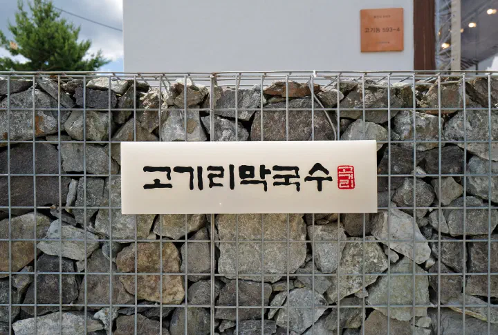 Gogiri Makguksu nameplate sign mounted on the gabion stone wall in Gogi-dong, Yongin