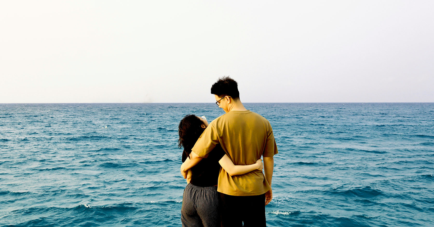 Andy and his partner standing by the sea