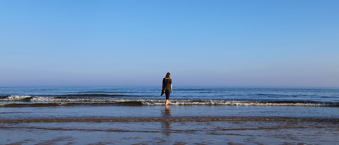 Person walking toward the sea and uncertain future