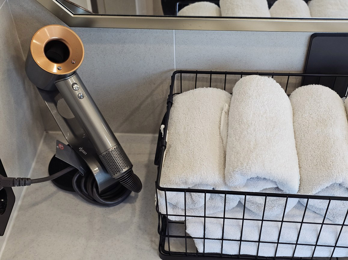 Dyson hair dryer and a stack of fresh towels in the room