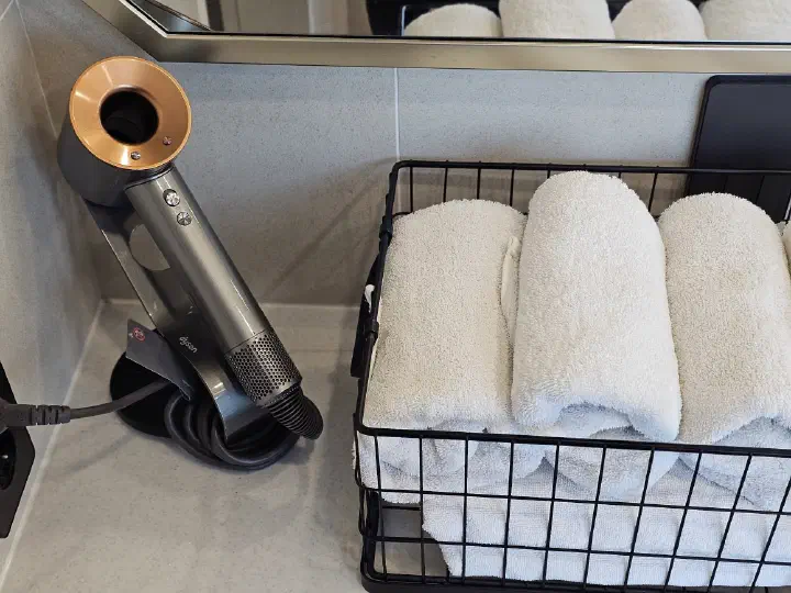 Dyson hair dryer and a stack of fresh towels in the room