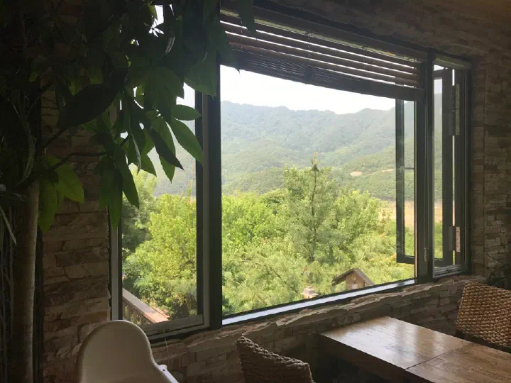 Green forest and mountain views through a Forest Resom guest room window